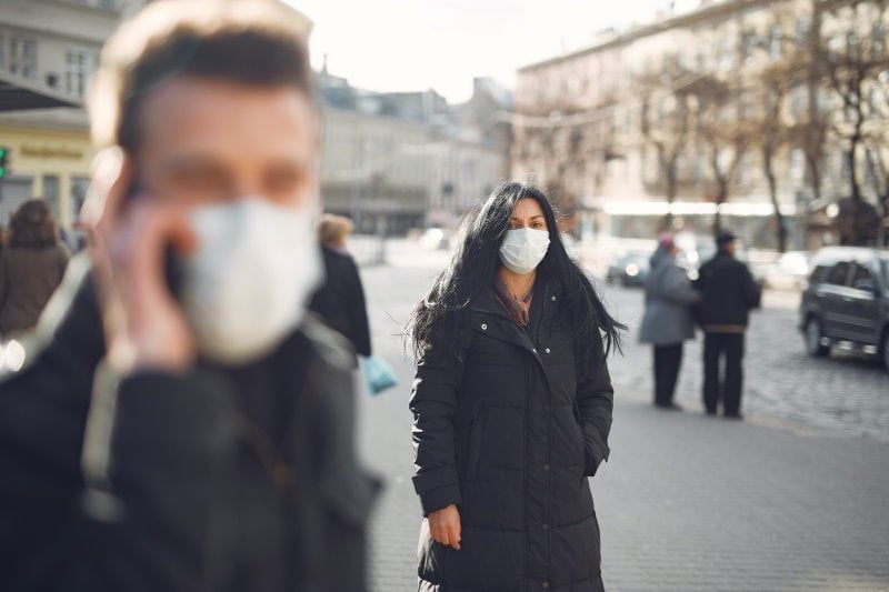 검은색과 마스크를 쓴 여자가 거리에 서 있다